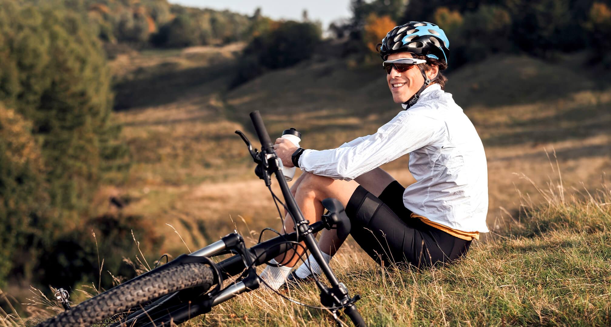 Person auf einem Hügel sitzend mit Mountainbike und Sonnenbrille